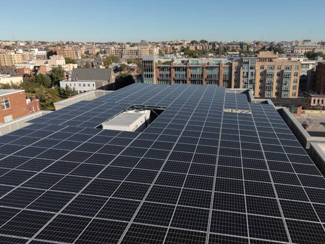Aerial view of the solar canopy covering the roof of 1441 Rhode Island Ave., with the city beyond