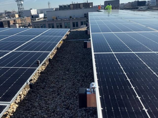Rows of solar panels with a roof walkway between them at 1909 Aurora Energy