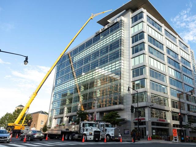 Mobile crane and delivery truck staged on the street outside 20 M Street