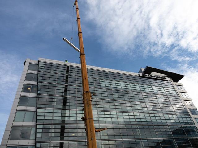 Crane boom rising past the glass facade of 20 M Street