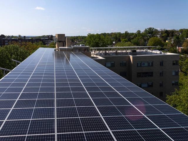 Solar canopy stretching along the roof of 3801 Connecticut Ave., with treetops beyond