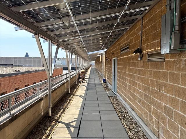 Roof walkway beneath the solar canopy along a brick wall at 616
