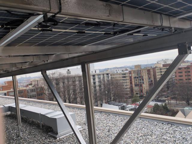 Solar canopy bracing at the roof edge of 925, with a city view