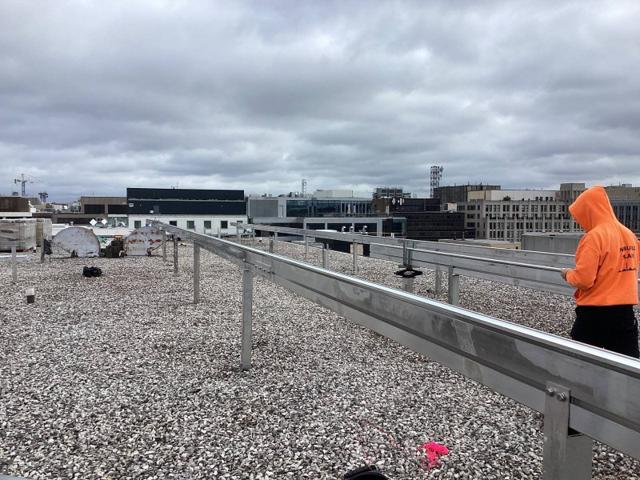Installer beside a long aluminum rail on the roof of Lafayette