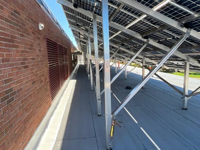Solar canopy supports beside the brick penthouse wall at Locke Hall