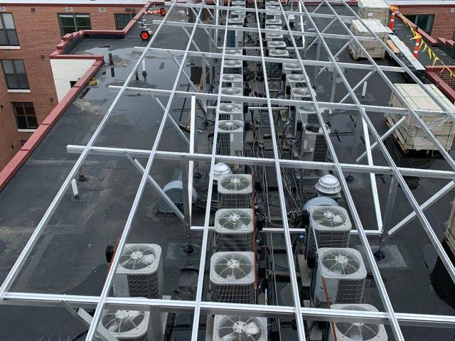 Aerial view of the racking frame over rows of rooftop condensers at Randolph Towers, before the panels