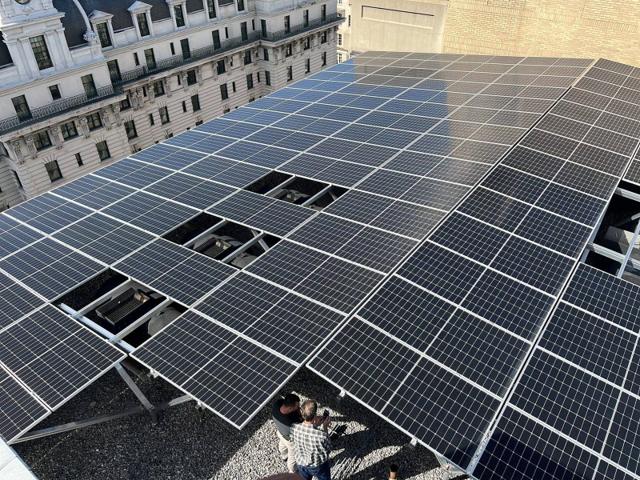 Aerial view of a rooftop solar array with openings over equipment