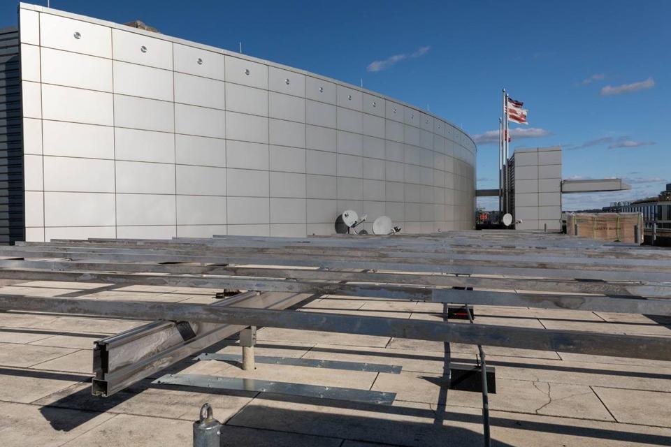 Aluminum racking frame under construction on the roof of 20 M Street, beside a curved metal penthouse wall